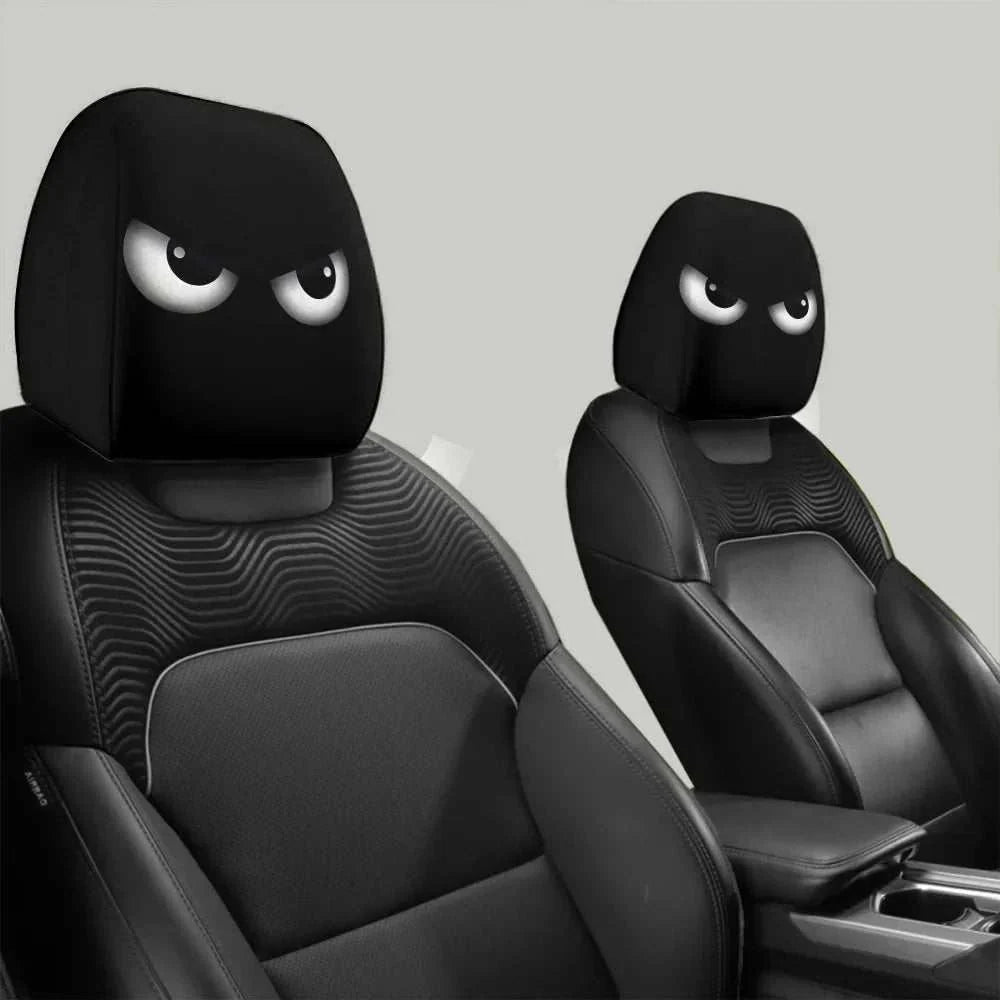 Funny Slanted Eyes black elastic headrest covers with cartoon white eyes, shown fitted over two car seats