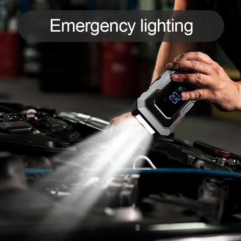 Portable Car Jump Starter in a black and gray casing with a blue digital display, illuminating a car engine bay