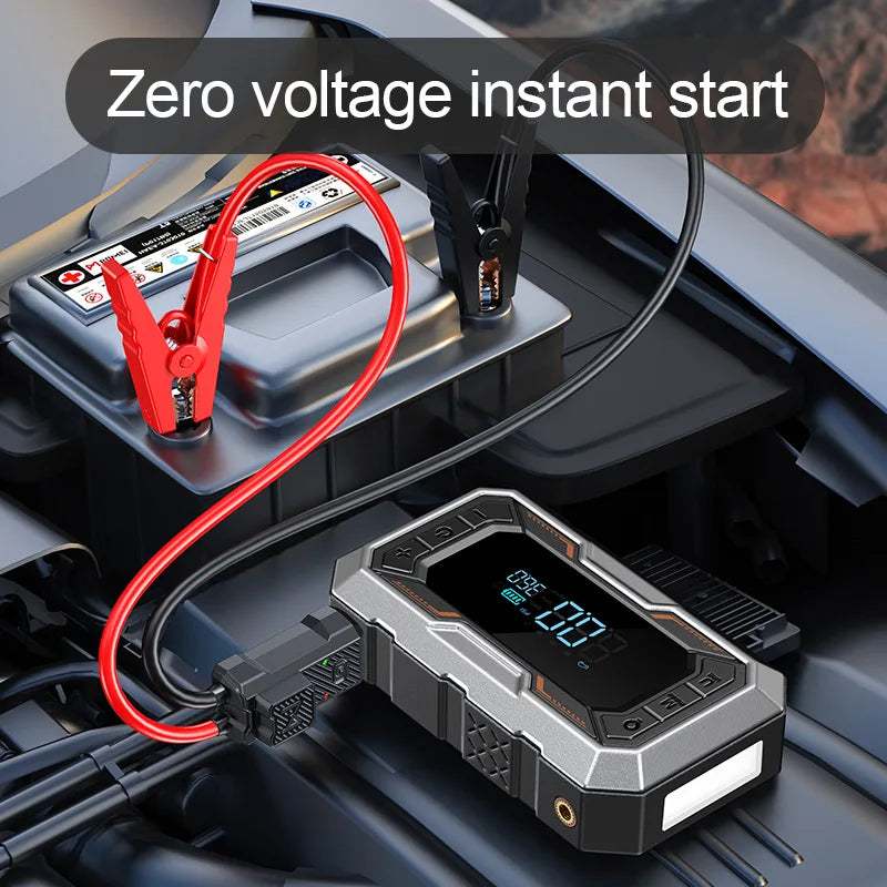 Portable Car Jump Starter in black and silver with a digital display, connected by red and black clamps to a car battery.