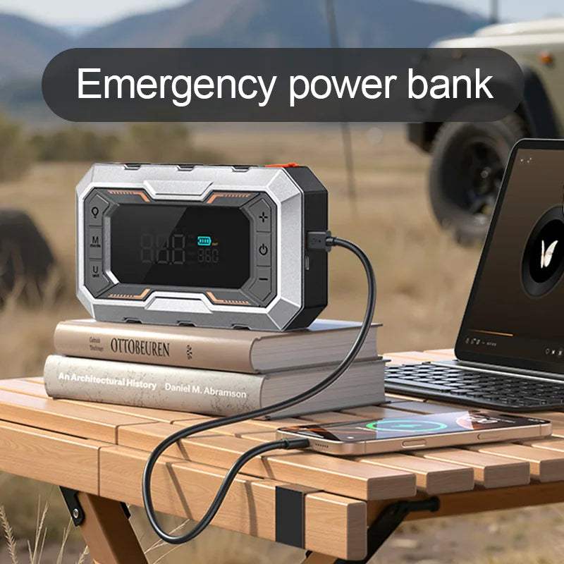 Portable Car Jump Starter in a silver and black rugged case, with a digital display and USB cable charging a phone
